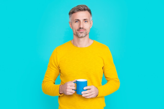 Smiling mature man at coffee break at studio mature man at coffee break on background photo of mature man at coffee break mature man at coffee break isolated on blue