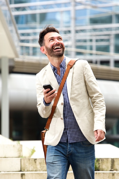 Uomo maturo sorridente all'aperto con il telefono cellulare