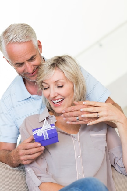 Smiling mature man surprising woman with a gift