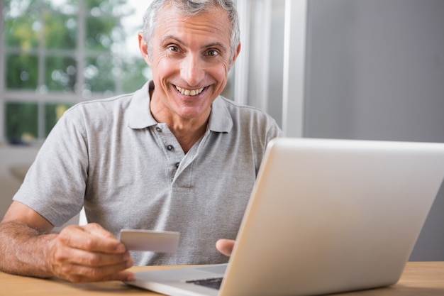 Uomo maturo sorridente che utilizza il suo computer portatile