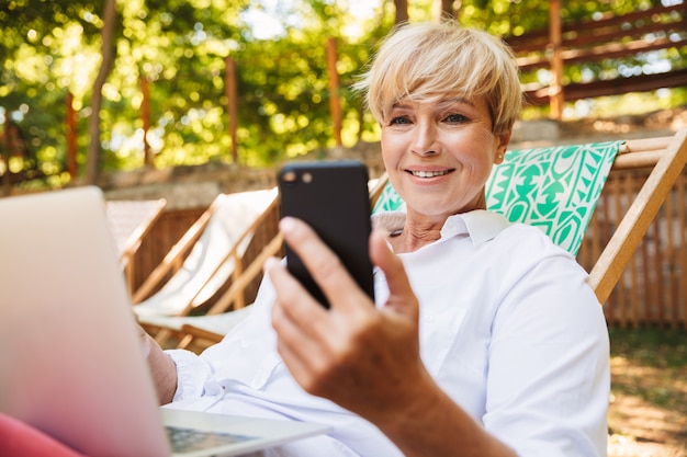 Smiling mature woman holding mobile phone
