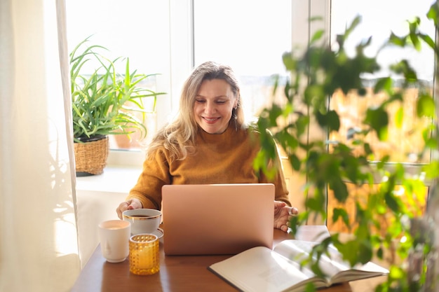 Donna matura sorridente che usa il portatile al caffè.