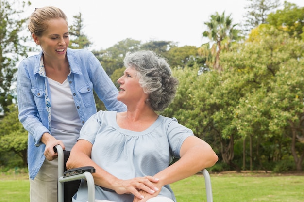 Smiling mature woman in wheelchair talking with daughter