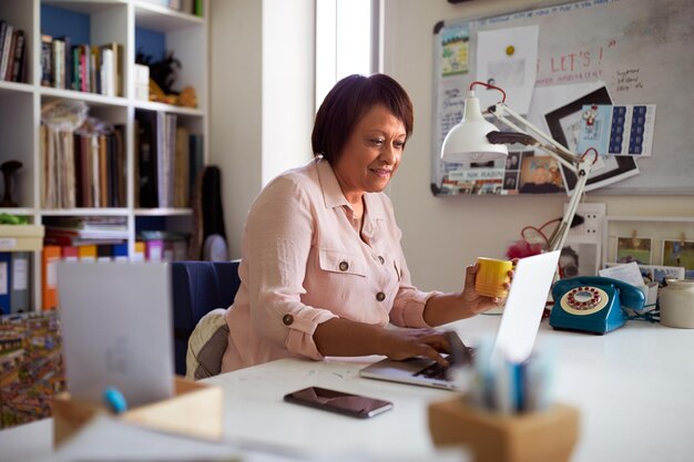 Smiling Mature Woman With Laptop Working In Home Office