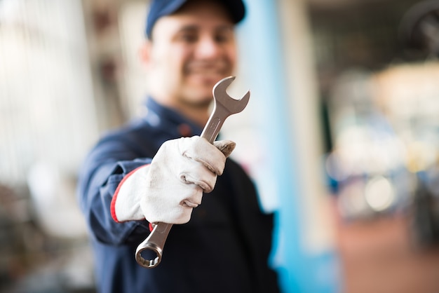 Smiling mechanic holding a wrench in his shop