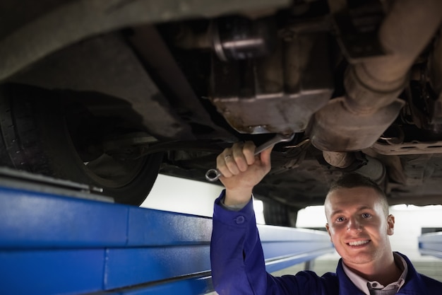 Smiling mechanic looking at camera while repairing