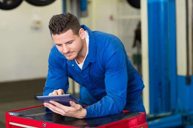 Photo smiling mechanic using his tablet