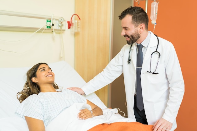 Smiling mid adult healthcare worker consoling young patient at hospital