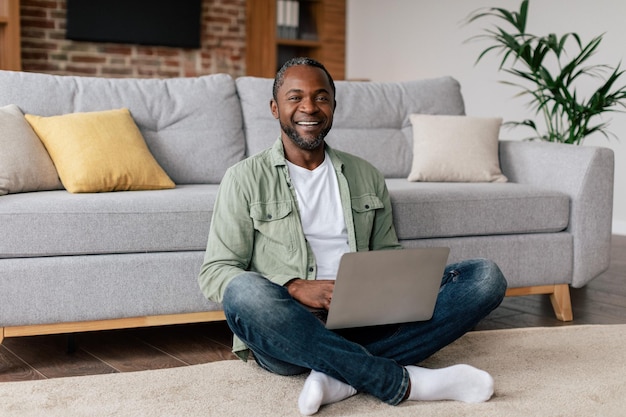 Smiling middle aged african american guy in casual typing on laptop have video call chat in social networks