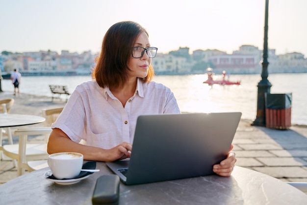 Smiling middle aged business woman in cafe with laptop