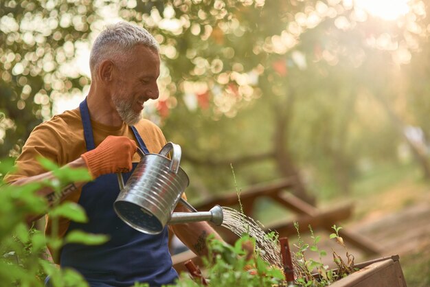 笑顔の中年白人男性の水やり植物