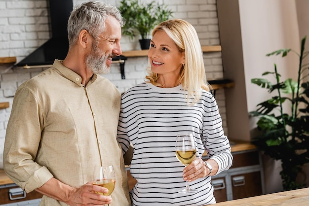 Smiling middle aged couple drinking wine and looking on each other