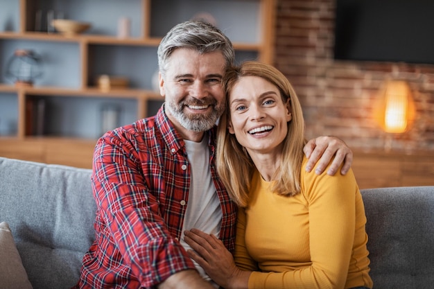 笑顔の中年ハンサムなヨーロッパの男性と女性がハグし、カメラを見て優しい瞬間を楽しむ