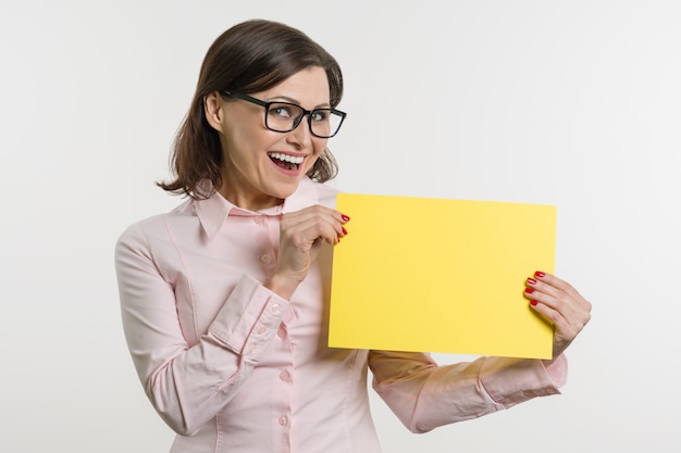 Smiling middle aged woman with yellow sheet of paper