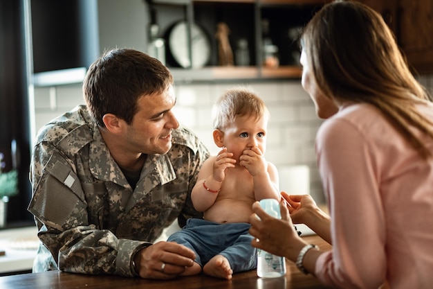 家で彼の赤ん坊の息子と妻と一緒に時間を過ごす笑顔の軍将校