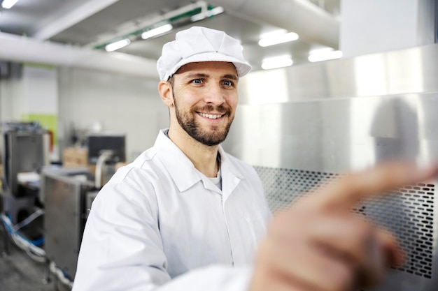 A smiling milk factory worker types on the display and programs a machine for milk pasteurization