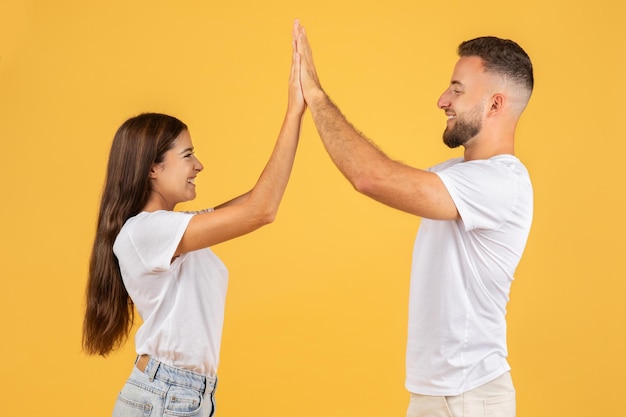 Smiling millennial european woman and guy give high five with hands enjoy win good news