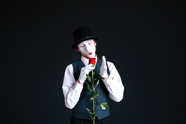 Smiling mime looks at pretty rose in his arms