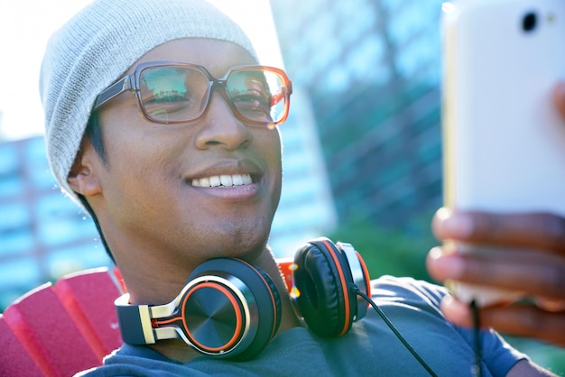 Sorridente ragazzo corse mista utilizzando la cuffia fuori nel parco