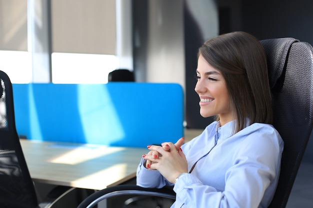 Smiling modern woman is thinking about business while working in the office.