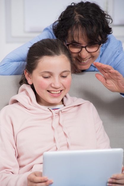 Smiling mom and daughter using  tablet computer at home