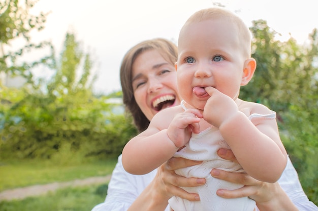 Улыбающаяся мама и маленькая блондинка дочка веселятся на свежем воздухе в саду на открытом воздухе счастливая семья