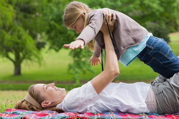 Smiling mother carrying daughter at park