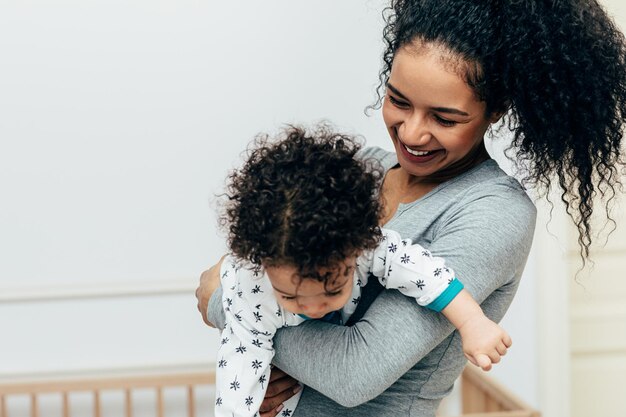 smiling mother carrying son at home