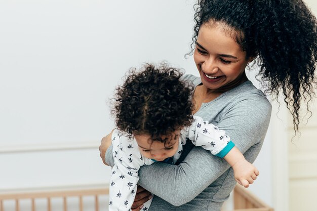 Photo smiling mother carrying son at home