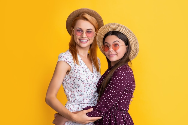 Smiling mother and child in straw hat on yellow background