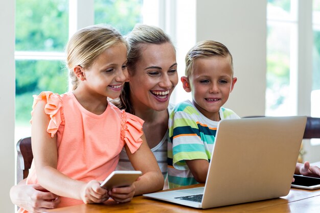 Smiling mother and children looking at laptop