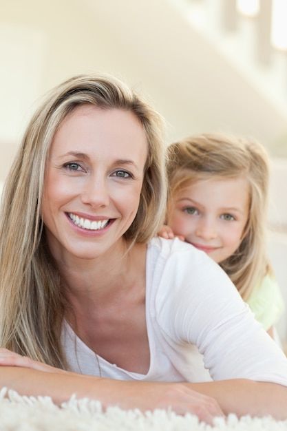 Photo smiling mother and daughter on the carpet