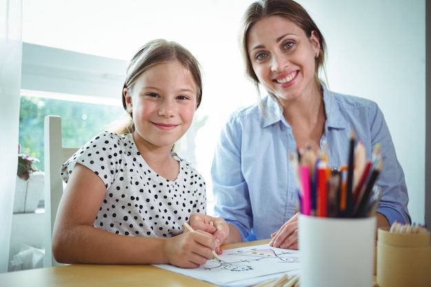 Smiling mother and daughter drawing together