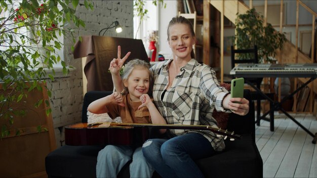 Photo smiling mother and daughter taking selfie at home