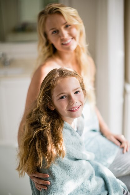 Photo smiling mother and daughter in towel at bathroom