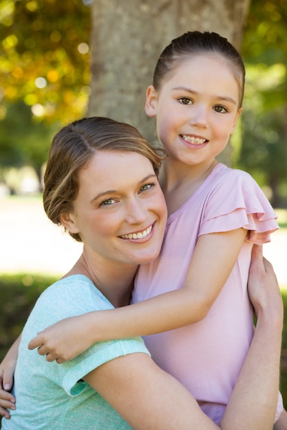 Smiling mother embracing her daughter at park