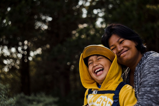 smiling mother embracing son in forest