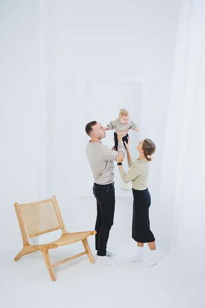 笑顔の母と父が子供を抱いている 両親の母と父親と笑顔の赤ちゃんが白い背景で孤立している 幸せな若い家族