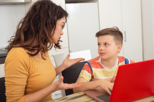 Smiling mother helping adorable son doing schoolwork at home