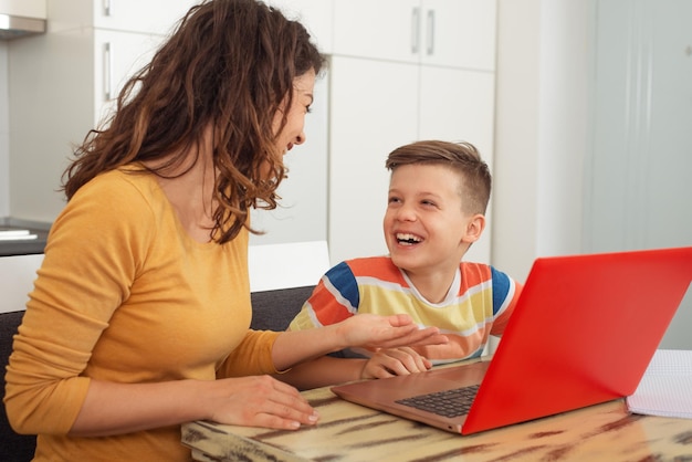 Smiling mother helping adorable son doing schoolwork at home