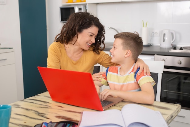 Smiling mother helping adorable son doing schoolwork at home