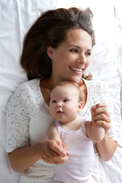 Smiling mother holding baby in bed