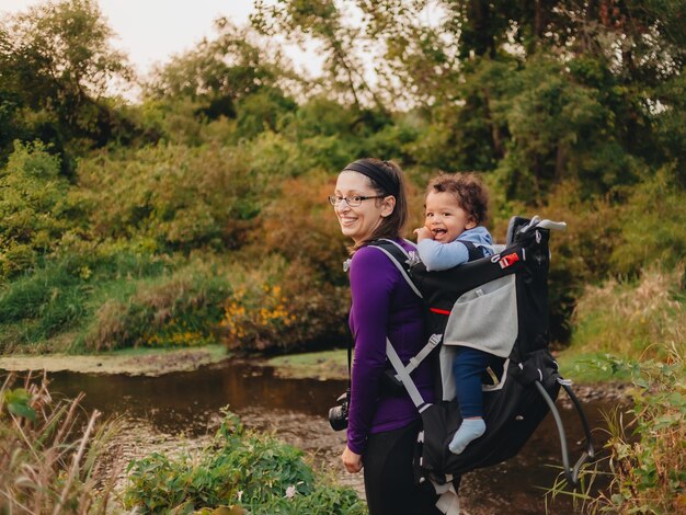 Photo smiling mother with cute son on back standing on forest