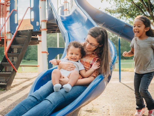 Foto madre sorridente con i bambini seduti sul lato al parco