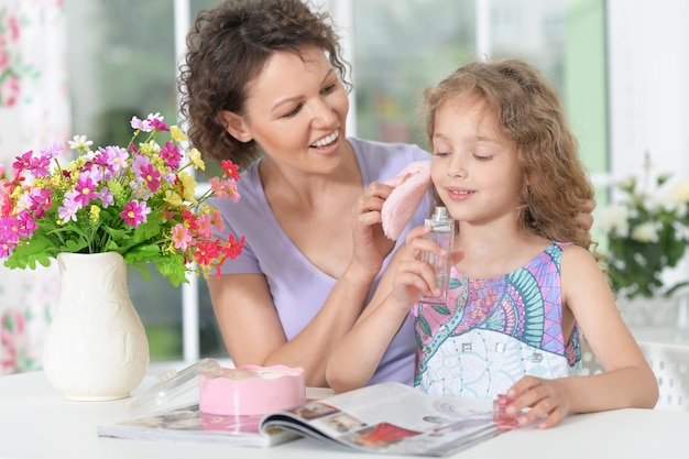 Smiling mother with little daughter  with magazine at home