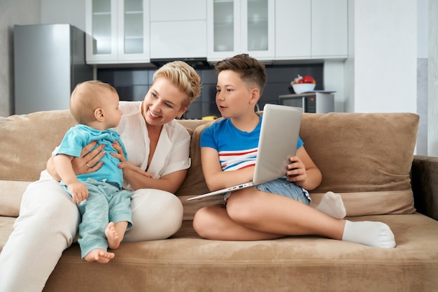 Smiling mother with two sons of playing on couch