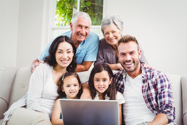 Smiling multi generation family using a laptop 