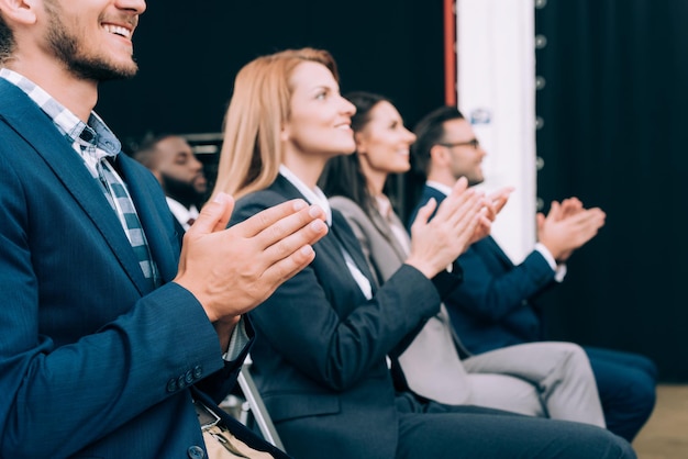 Smiling multicultural businesspeople applauding during business seminar in conference hall