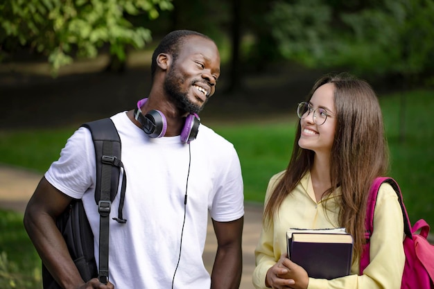 Smiling multicultural students communicate in campus park