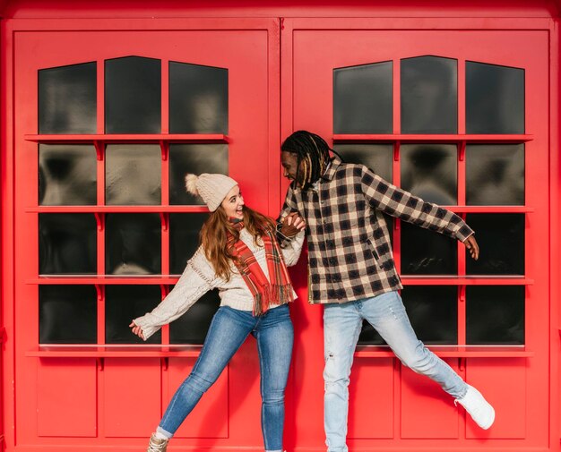 Smiling multiracial couple having fun outdoors red doors on the background